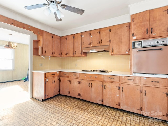 kitchen with light floors, oven, light countertops, under cabinet range hood, and stainless steel gas stovetop