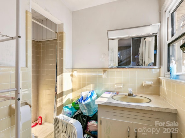 bathroom featuring a stall shower, tile walls, and vanity