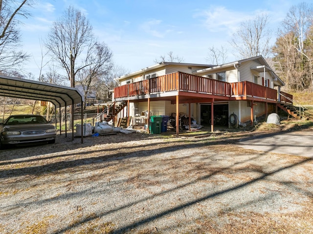 back of house featuring dirt driveway, a wooden deck, stairs, and a detached carport