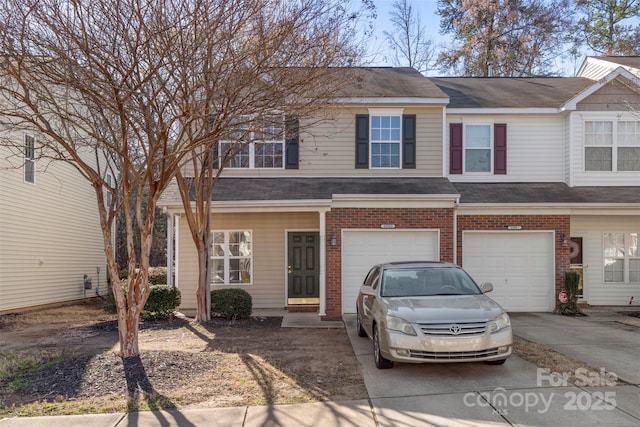 multi unit property featuring brick siding, a garage, driveway, and a shingled roof