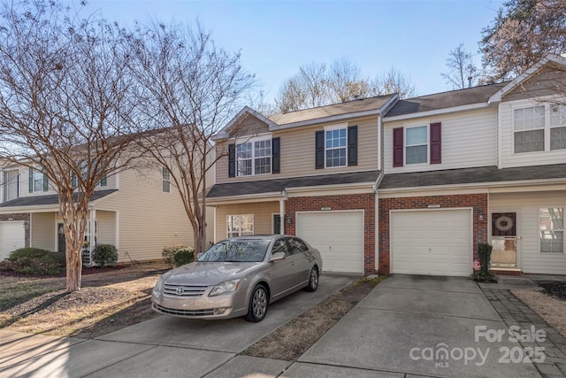 view of property featuring a garage, brick siding, and driveway