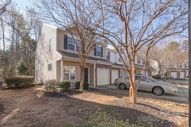 multi unit property featuring a garage, brick siding, and concrete driveway