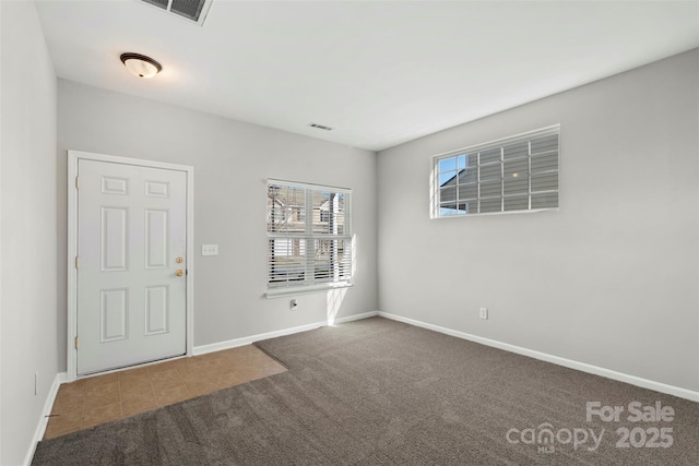 interior space featuring tile patterned floors, visible vents, baseboards, and carpet