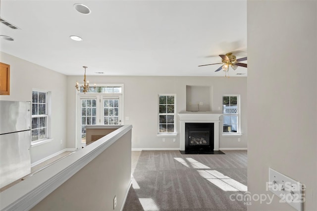 unfurnished living room featuring visible vents, baseboards, a fireplace with flush hearth, light colored carpet, and recessed lighting