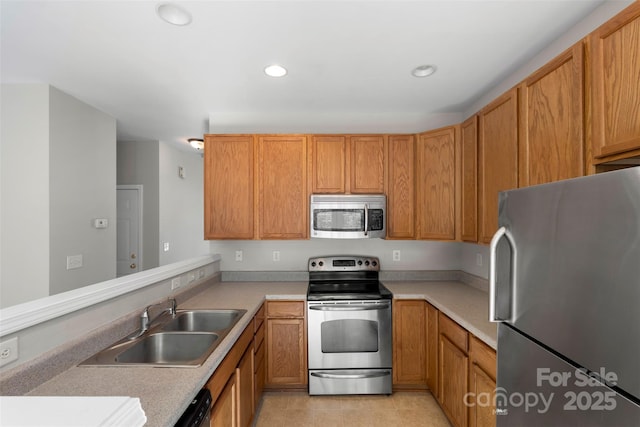 kitchen with a sink, recessed lighting, appliances with stainless steel finishes, a peninsula, and light countertops