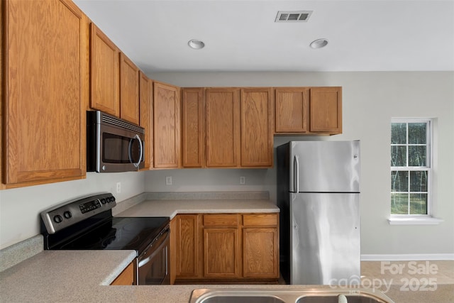 kitchen featuring brown cabinetry, visible vents, appliances with stainless steel finishes, and light countertops