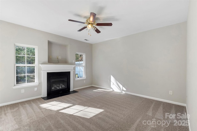 unfurnished living room featuring carpet flooring, baseboards, a fireplace with flush hearth, and ceiling fan