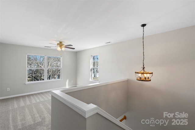 hallway with visible vents, baseboards, light carpet, an upstairs landing, and a chandelier