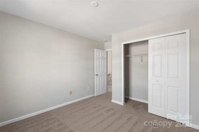 unfurnished bedroom featuring a closet, baseboards, and carpet flooring