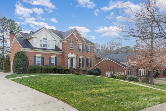 view of front of house featuring a chimney, a front lawn, and brick siding