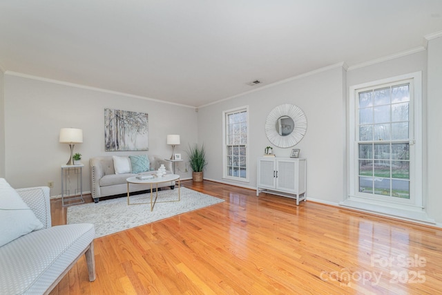 living area with baseboards, crown molding, visible vents, and wood finished floors