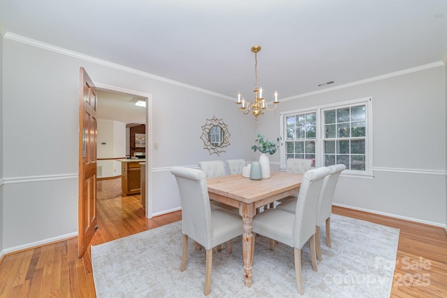 dining space with baseboards, light wood-type flooring, a chandelier, and crown molding