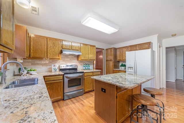 kitchen featuring a center island, stainless steel electric range oven, visible vents, a sink, and under cabinet range hood