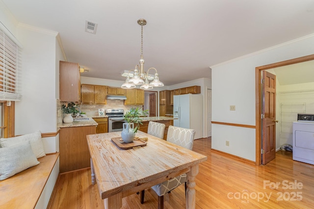 dining area with washer / dryer, crown molding, and light wood-style flooring