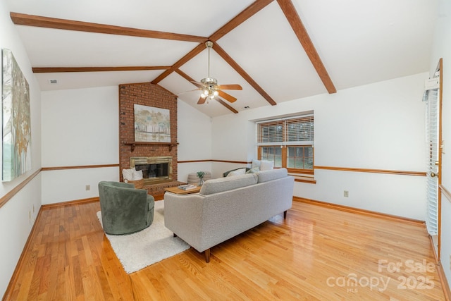 living area with vaulted ceiling with beams, a fireplace, a ceiling fan, wood finished floors, and baseboards