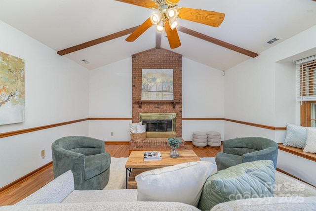 living area featuring a fireplace, visible vents, lofted ceiling with beams, wood finished floors, and baseboards