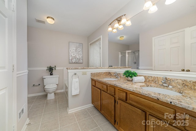 bathroom with double vanity, a sink, a shower stall, and tile patterned floors