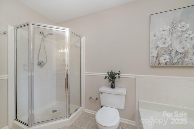 full bath with a stall shower, tile patterned flooring, toilet, and a bath