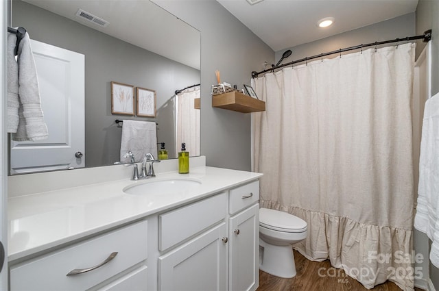 full bath featuring toilet, visible vents, wood finished floors, and vanity