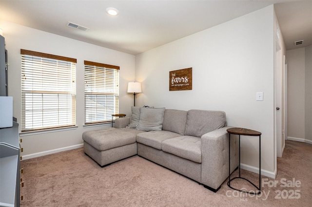 living area with carpet, visible vents, and baseboards