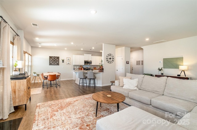 living area with baseboards, light wood finished floors, visible vents, and recessed lighting