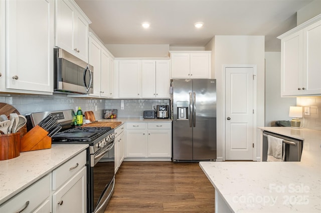 kitchen featuring stainless steel appliances, dark wood finished floors, white cabinetry, and light stone countertops