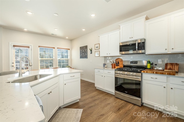 kitchen with backsplash, appliances with stainless steel finishes, dark wood finished floors, and a sink