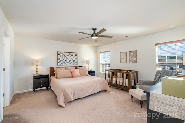 bedroom featuring a ceiling fan, light colored carpet, visible vents, and multiple windows