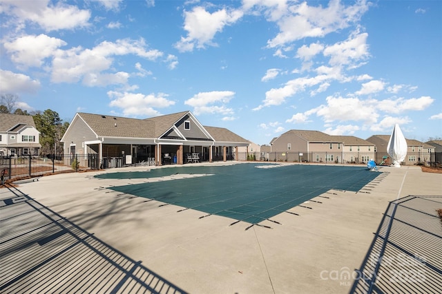 pool with a patio area, fence, and a residential view