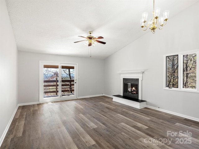 unfurnished living room with dark wood-style flooring, a glass covered fireplace, vaulted ceiling, baseboards, and ceiling fan with notable chandelier