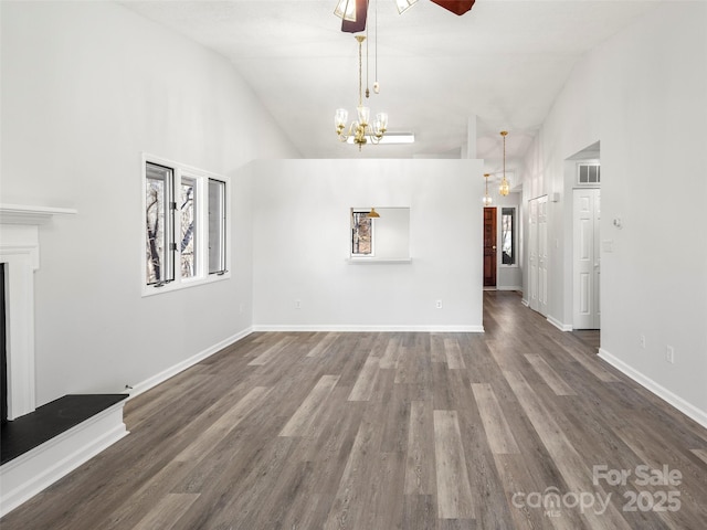 unfurnished living room with a fireplace with raised hearth, visible vents, wood finished floors, a chandelier, and baseboards