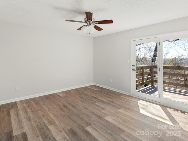 spare room with baseboards, visible vents, ceiling fan, wood finished floors, and a textured ceiling