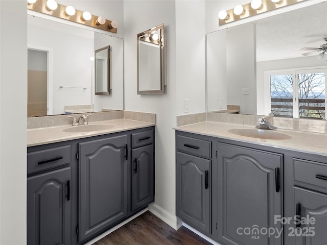 bathroom featuring ceiling fan, two vanities, and a sink