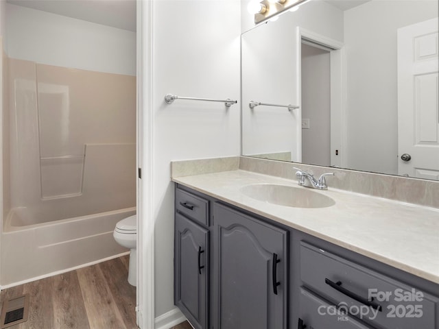 bathroom featuring bathtub / shower combination, visible vents, toilet, vanity, and wood finished floors