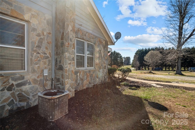 view of side of home featuring stone siding and central AC unit