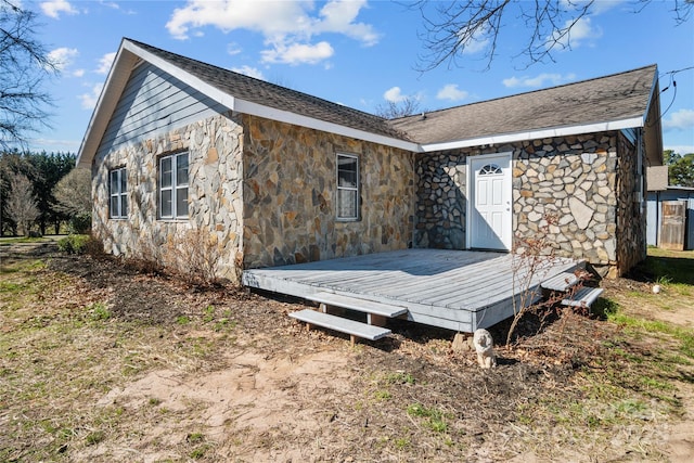 rear view of house featuring a shingled roof and a wooden deck