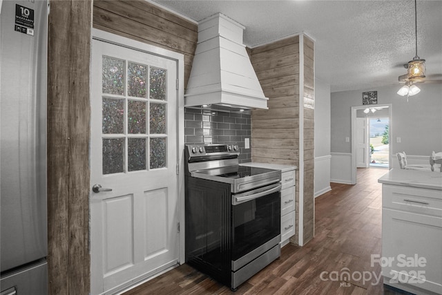 kitchen featuring a textured ceiling, stainless steel appliances, custom exhaust hood, and dark wood finished floors