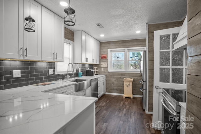 kitchen featuring stainless steel appliances, visible vents, plenty of natural light, and light stone countertops