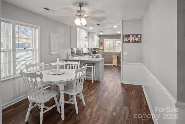 dining space featuring visible vents, dark wood finished floors, baseboards, and ceiling fan