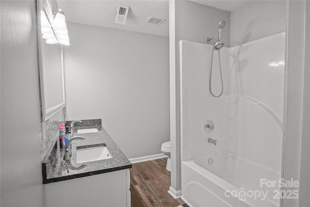 full bath with a sink, a textured ceiling, toilet, and wood finished floors