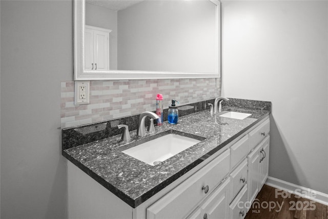 bathroom with a sink, backsplash, baseboards, and double vanity