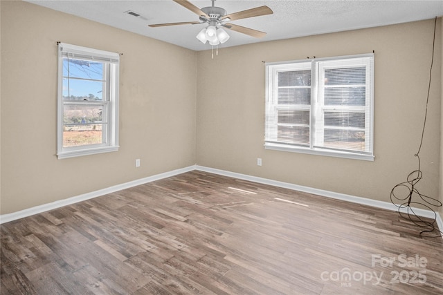 spare room with ceiling fan, wood finished floors, visible vents, and baseboards