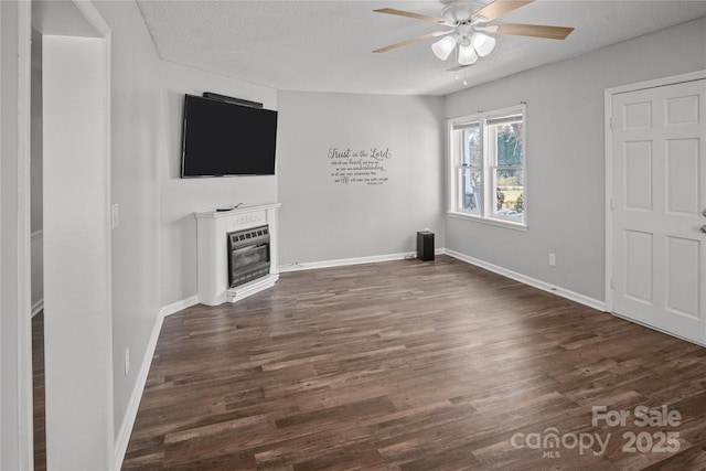 unfurnished living room featuring a glass covered fireplace, dark wood finished floors, a textured ceiling, and ceiling fan