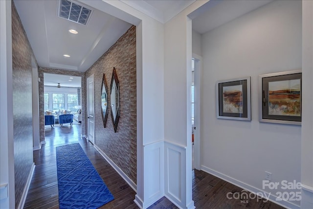 hall featuring visible vents, baseboards, and wood finished floors