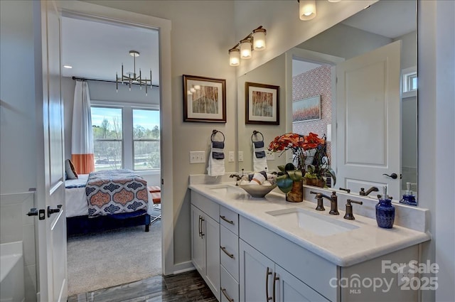ensuite bathroom featuring double vanity, a sink, connected bathroom, and wood finished floors