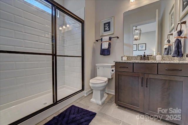 bathroom featuring a shower stall, vanity, baseboards, and toilet