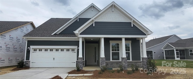 craftsman house with stone siding, covered porch, a garage, and concrete driveway
