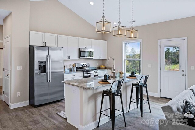 kitchen with stainless steel appliances, a breakfast bar, an island with sink, and white cabinets