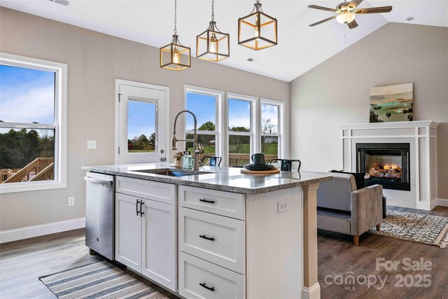 kitchen featuring dark wood-style flooring, a sink, white cabinetry, and light stone countertops