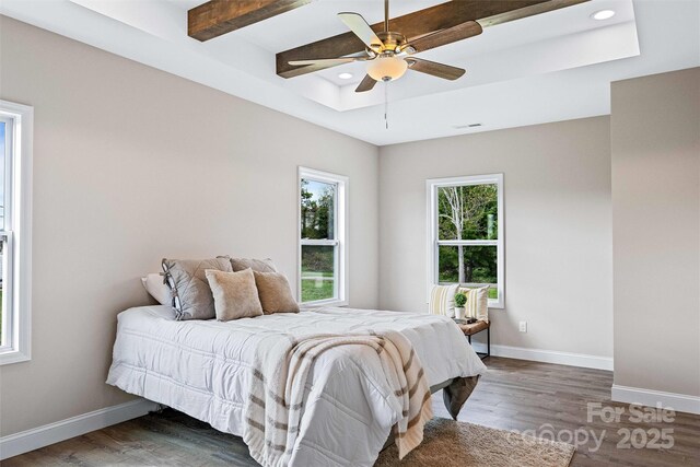 bedroom featuring a tray ceiling, baseboards, and wood finished floors